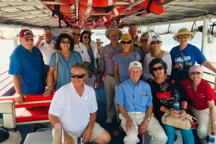 Group of people smiling on a boat under life jackets.
